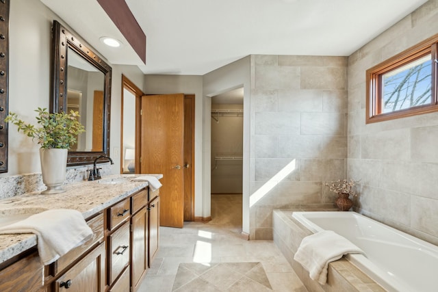 bathroom with vanity, a garden tub, and a walk in closet