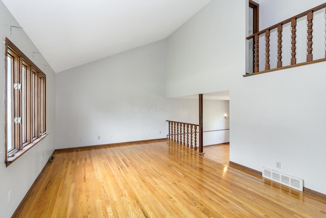 unfurnished living room with hardwood / wood-style floors and high vaulted ceiling