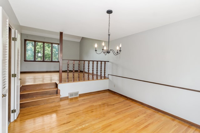 empty room featuring hardwood / wood-style flooring and an inviting chandelier