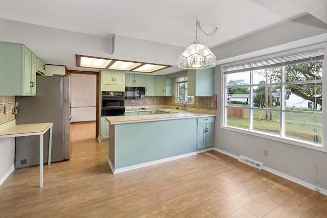 kitchen featuring tasteful backsplash, black appliances, light hardwood / wood-style flooring, green cabinetry, and a notable chandelier