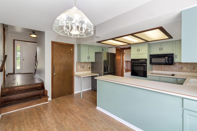 kitchen featuring black appliances, pendant lighting, hardwood / wood-style flooring, and green cabinetry