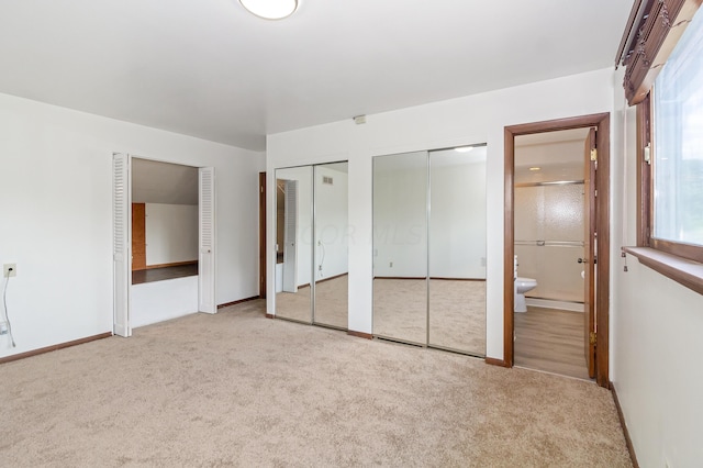 unfurnished bedroom with light carpet, connected bathroom, and multiple closets