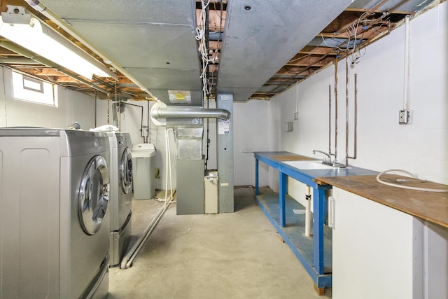 basement featuring heating unit, sink, and washer and dryer