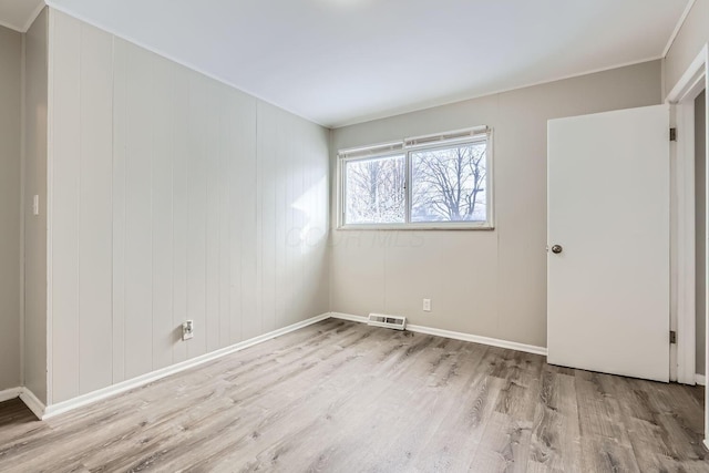 empty room with wood finished floors, visible vents, and baseboards