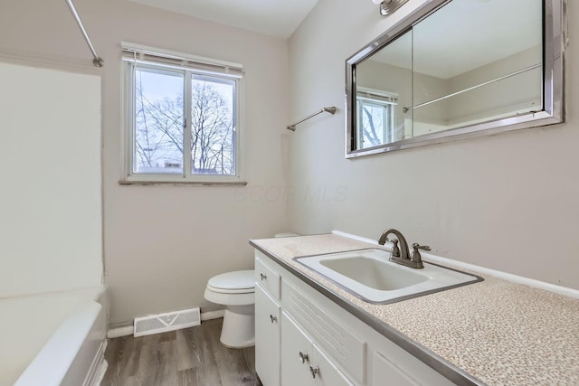 full bathroom with visible vents, toilet, vanity, wood finished floors, and baseboards