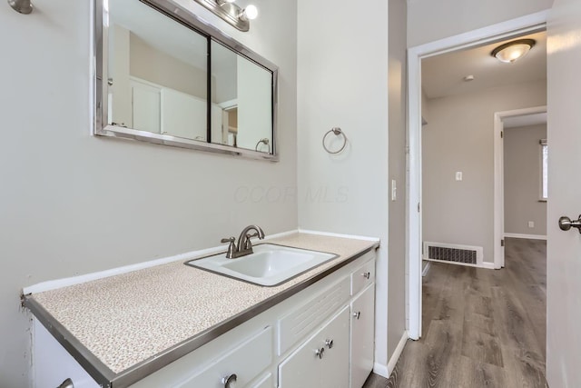 bathroom with visible vents, vanity, baseboards, and wood finished floors