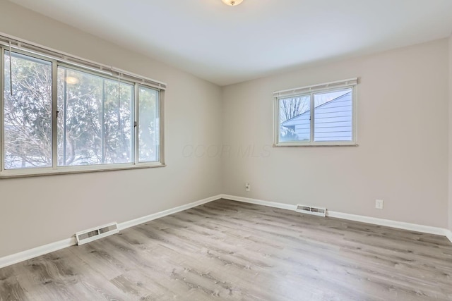 spare room featuring plenty of natural light, visible vents, and baseboards