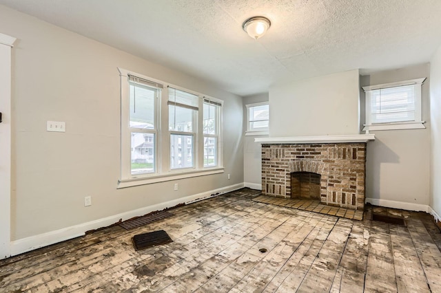 737 S Richardson Ave, Columbus, OH 43204 - unfurnished living room with wood-type flooring, a brick fireplace, and a textured ceiling