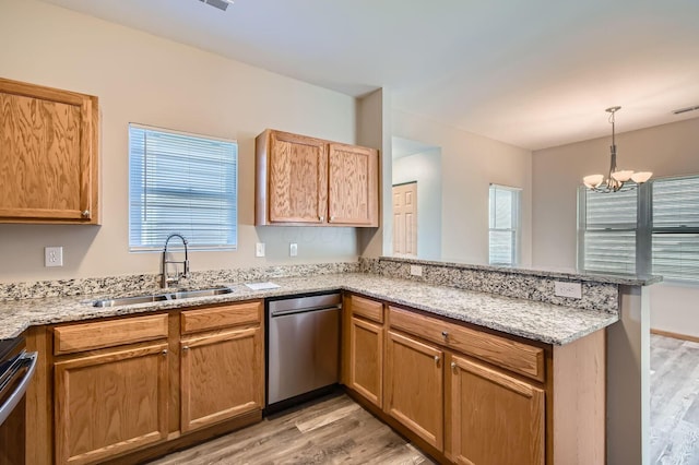 kitchen featuring a sink, a peninsula, light wood-type flooring, stainless steel dishwasher, and a notable chandelier