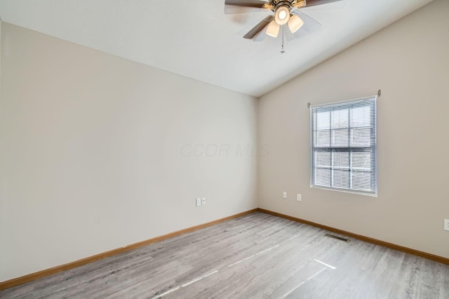 spare room with vaulted ceiling, light wood finished floors, baseboards, and visible vents