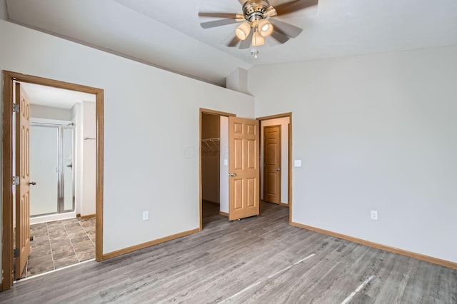 unfurnished bedroom featuring baseboards, lofted ceiling, a closet, and wood finished floors