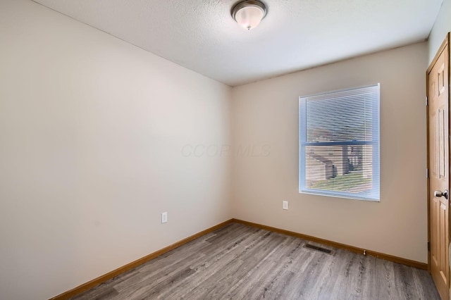 spare room with baseboards, light wood-style floors, and visible vents
