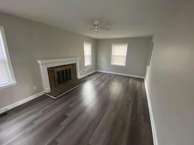 unfurnished living room featuring ceiling fan, a fireplace, and dark wood-type flooring