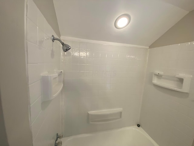 bathroom with vaulted ceiling and tiled shower / bath