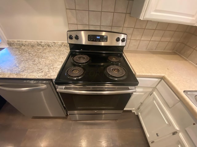 kitchen with white cabinets, appliances with stainless steel finishes, tasteful backsplash, and dark tile patterned floors