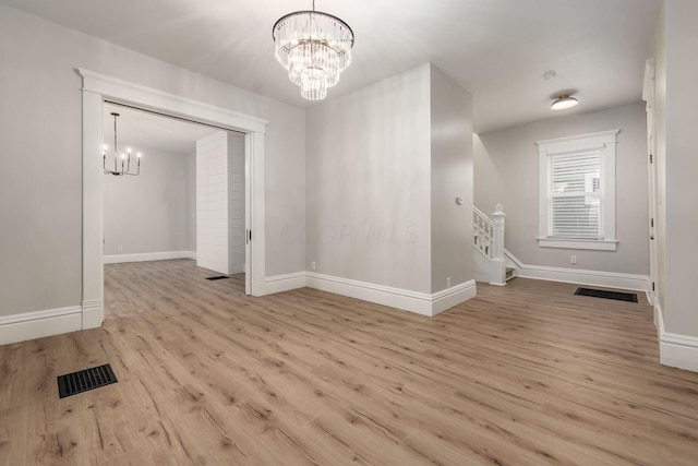 spare room with light hardwood / wood-style floors and an inviting chandelier