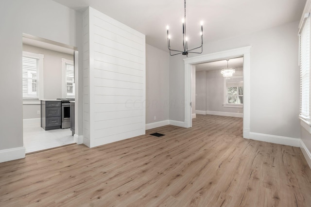 unfurnished dining area with a chandelier and light hardwood / wood-style flooring