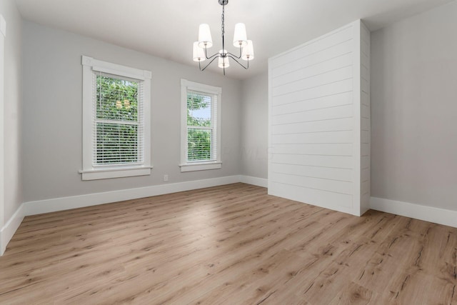 spare room featuring an inviting chandelier and light hardwood / wood-style flooring