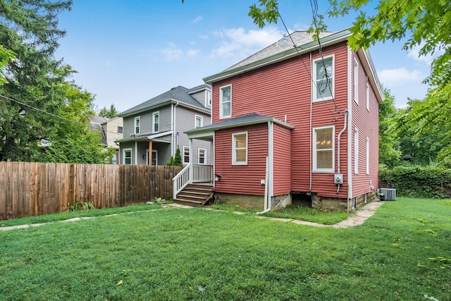 rear view of house featuring a yard and central AC