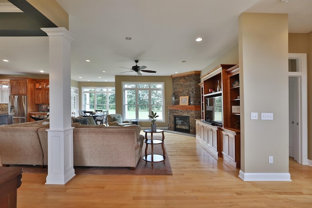 living room featuring a fireplace, decorative columns, ceiling fan, and light hardwood / wood-style floors