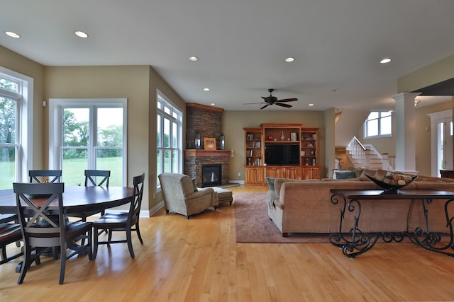 living room featuring decorative columns, a fireplace, a healthy amount of sunlight, and light hardwood / wood-style floors