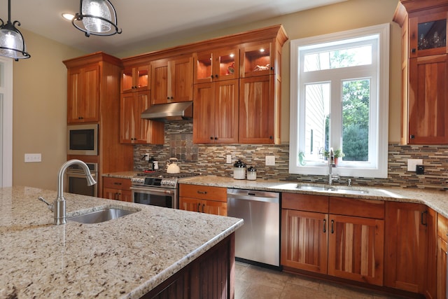 kitchen with sink, light stone countertops, stainless steel appliances, and hanging light fixtures