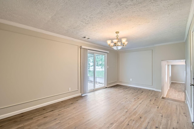 empty room featuring a chandelier, wood finished floors, a textured ceiling, ornamental molding, and baseboards