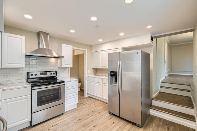 kitchen with stainless steel appliances, wall chimney range hood, white cabinetry, backsplash, and recessed lighting