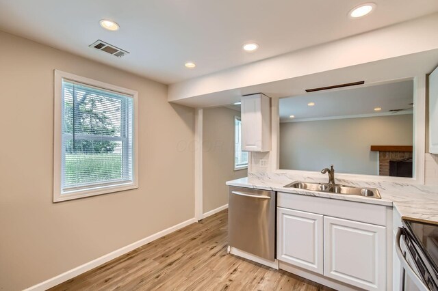 kitchen with appliances with stainless steel finishes, a sink, backsplash, white cabinetry, and light wood-style floors