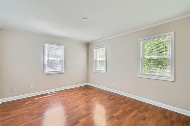 spare room featuring crown molding, baseboards, and wood finished floors