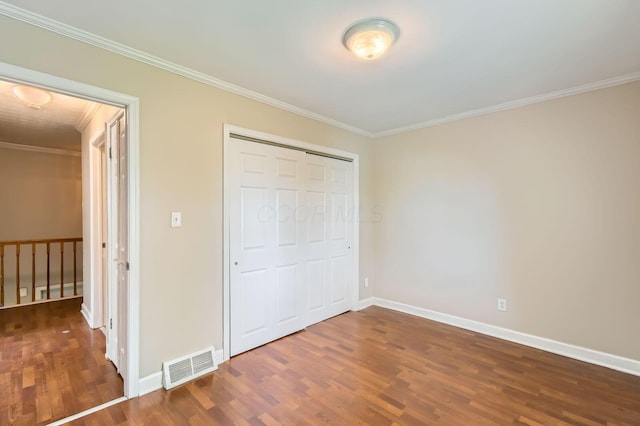 unfurnished bedroom with crown molding, wood finished floors, baseboards, and a closet