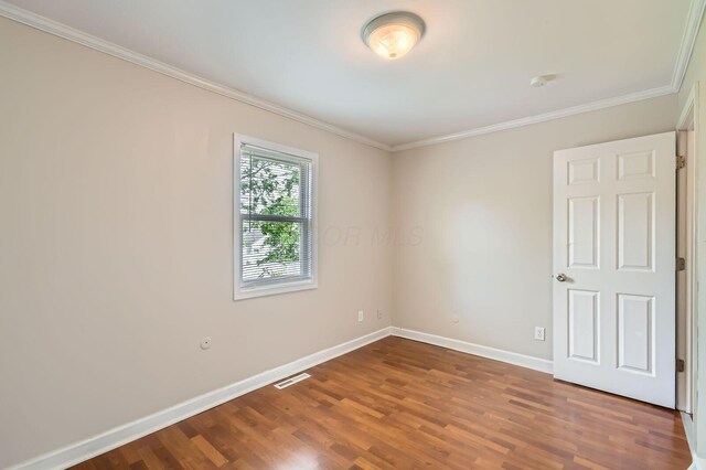 empty room with baseboards, ornamental molding, and wood finished floors