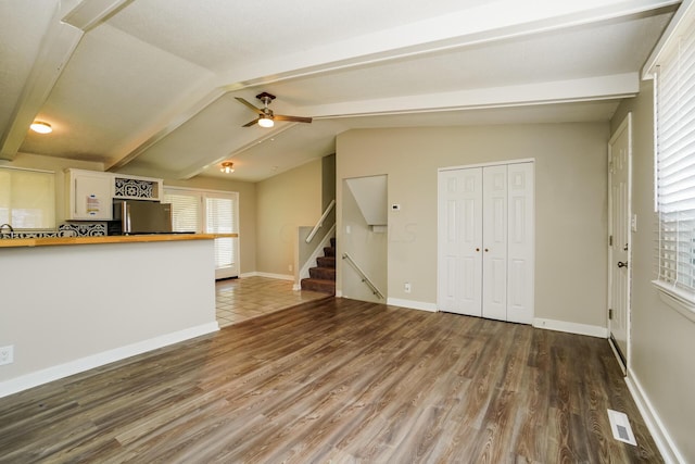 unfurnished living room with wood-type flooring, lofted ceiling with beams, and ceiling fan