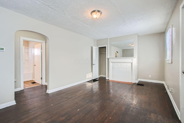 191 S Eureka Ave, Columbus, OH 43204 - unfurnished living room featuring hardwood / wood-style flooring, a textured ceiling, and arched walkways