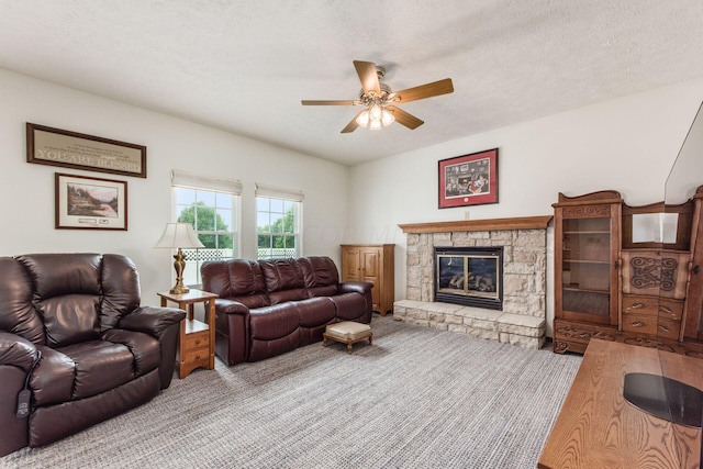 living room featuring a fireplace, a textured ceiling, and ceiling fan