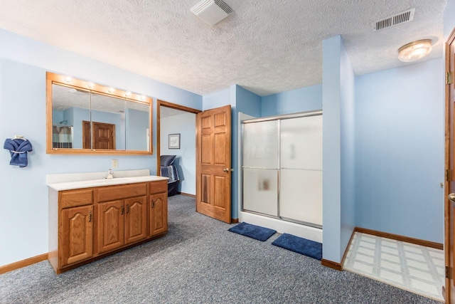 bathroom with vanity, an enclosed shower, and a textured ceiling