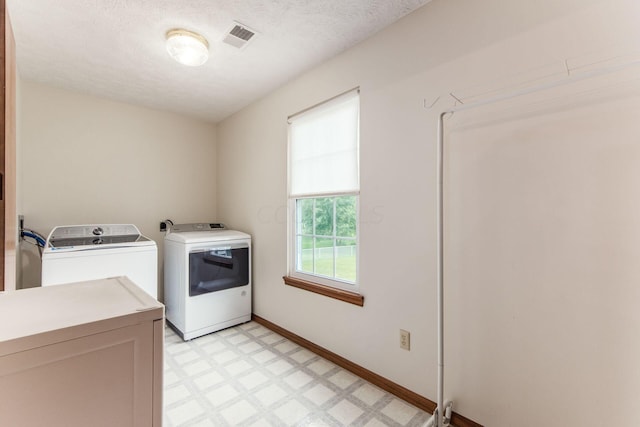 washroom featuring washer and clothes dryer, cabinets, and a textured ceiling