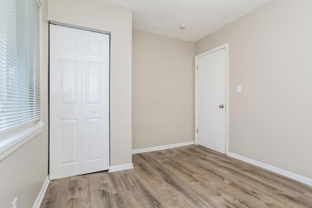 unfurnished bedroom with light hardwood / wood-style flooring and a closet