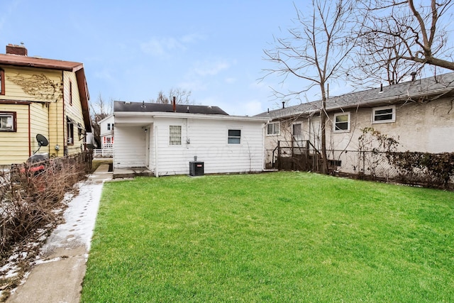 rear view of property with central AC and a lawn