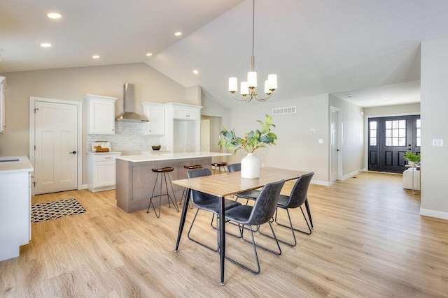 dining space featuring a chandelier, visible vents, vaulted ceiling, and light wood finished floors