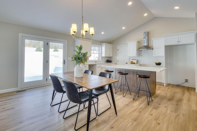 dining space with high vaulted ceiling, an inviting chandelier, light hardwood / wood-style floors, and sink