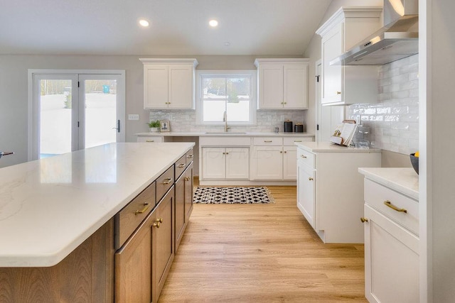 kitchen featuring sink, white cabinetry, tasteful backsplash, and wall chimney exhaust hood