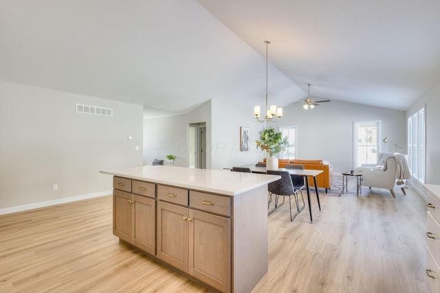 kitchen featuring pendant lighting, a center island, lofted ceiling, light wood-type flooring, and ceiling fan with notable chandelier