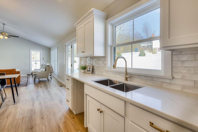 kitchen featuring sink, white cabinets, lofted ceiling, light hardwood / wood-style floors, and backsplash