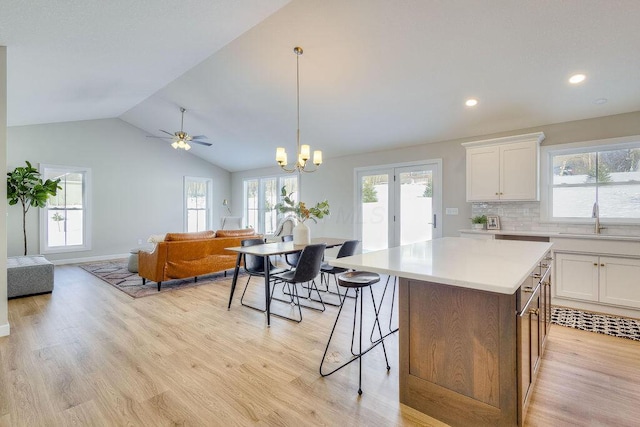 kitchen featuring sink, white cabinets, tasteful backsplash, and a center island