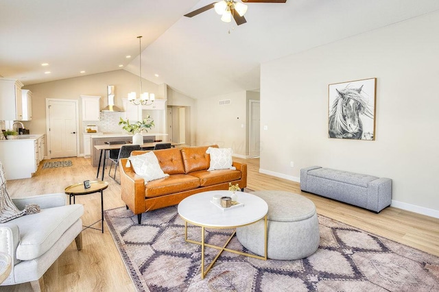 living area with lofted ceiling, ceiling fan with notable chandelier, baseboards, and light wood-style floors