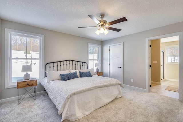 bedroom with light carpet, ceiling fan, and a textured ceiling