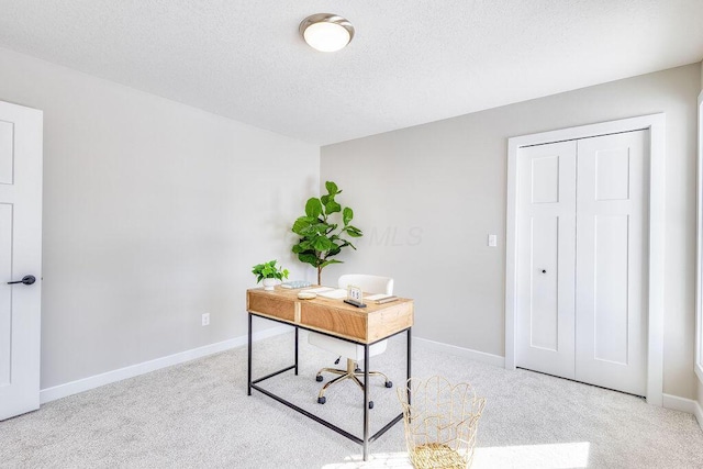 carpeted office space with a textured ceiling and baseboards