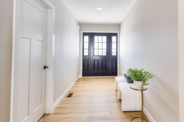 entryway featuring visible vents, light wood-style flooring, baseboards, and a textured ceiling