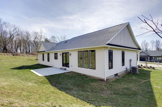 back of property with board and batten siding, a patio area, a yard, and a shingled roof